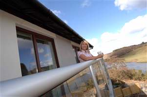 Side view of woman standing on her balcony leaning on the silver handrail