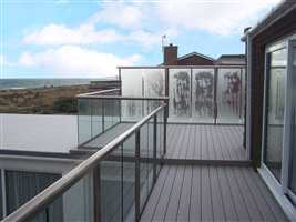 Royal Chrome handrail and posts with clear glass and privacy screens on the coast