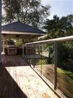 Long silver balustrading to a covered BBQ area surrounded by beautiful gardens