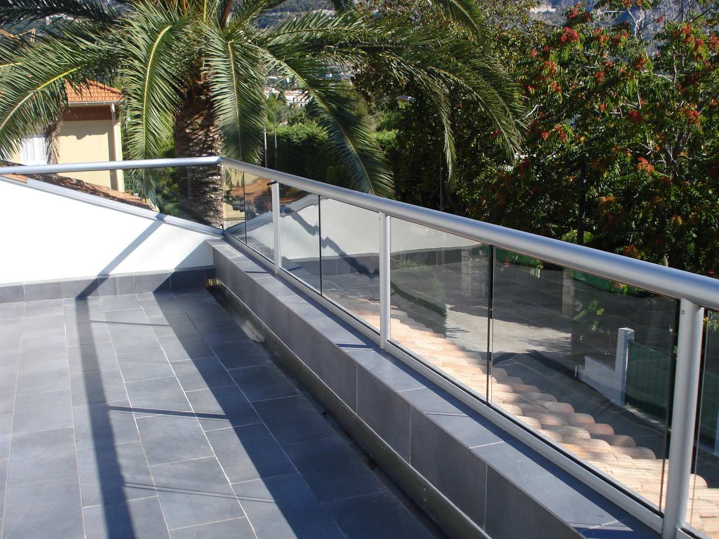  Silver Orbit Glass Balustrade looking over a sunny garden with a palm tree