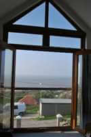 Looking out through a Juliet balcony with a Royal Chrome handrail to the seaside and blue skies