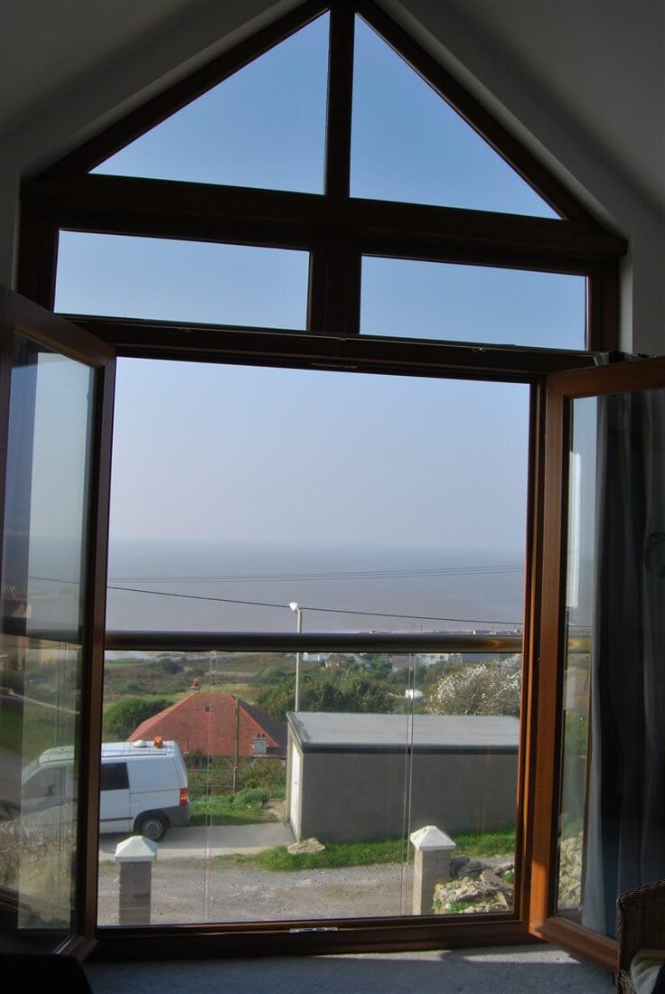 Looking out through a Juliet balcony with a Royal Chrome handrail to the seaside and blue skies