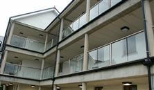 A 33-metre glass balustrade topped with a white powder-coated handrail turned into a perfect solution for a windy garden in Isle of Man property.