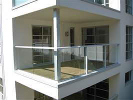 Spacious balcony with white handrails and posts on the corner of the building