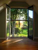 Looking out through a Royal Chrome Juliet balcony to beautiful gardens and sunshine