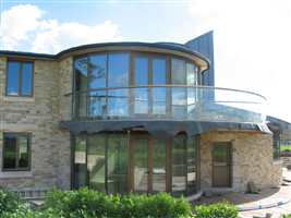 Large Curved semi frameless balcony in the sun with a Bronze handrail