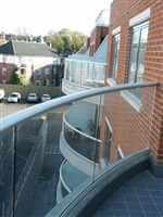 Curved balconies with silver handrails and dividing privacy screens in between properties