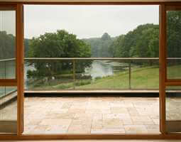 Looking out from inside through the clear glass balcony to the river and countryside