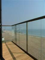 Looking through the corner of a balcony with bronze handrail to the sea