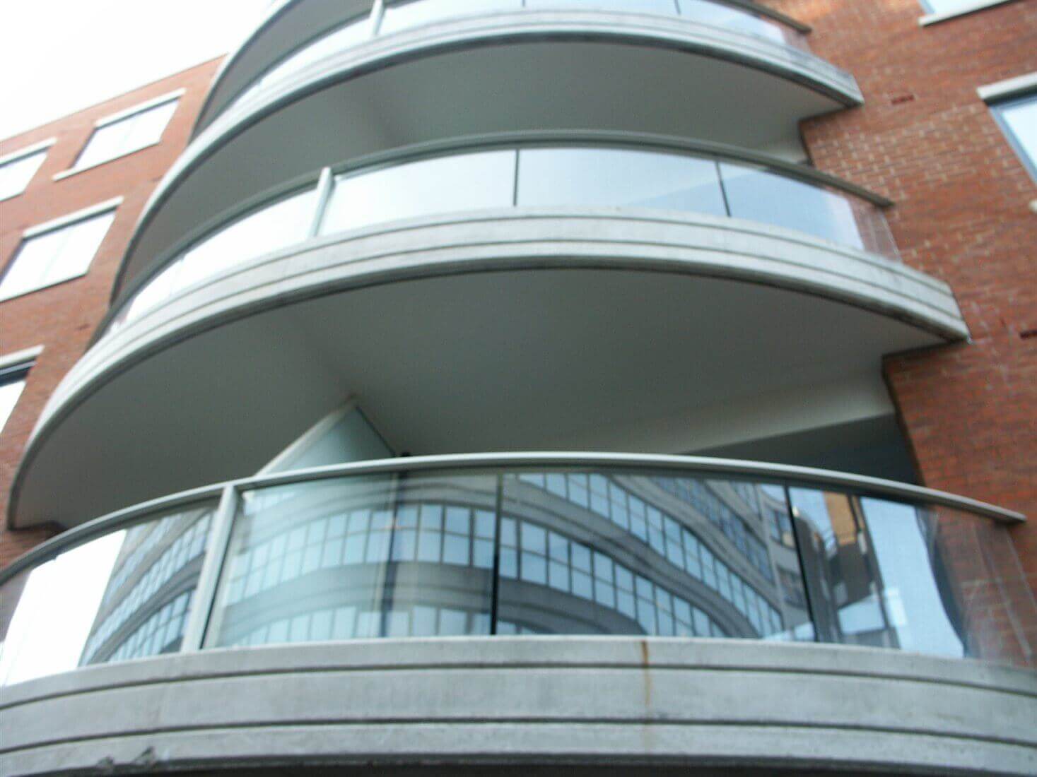 Curved balconies with silver handrails and posts on brick building