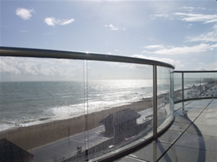 Curved balcony with a Royal Chrome handrails and posts with a view of the beach and blue skies