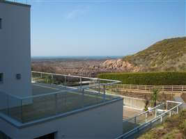 White balconies and balustrades on large white house overlooking amazing coast views