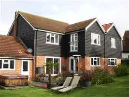 Small Juliet balcony with silver handrail on large house with sunloungers in the garden