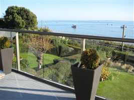 Bronze bal 2 balcony with clear glass overlooking the train track and the sea