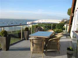 Bronze handrail and clear glass balcony overlooking the beautiful sea with blue skies