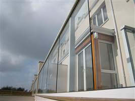 Looking side on at a clear glass balcony with white handrails