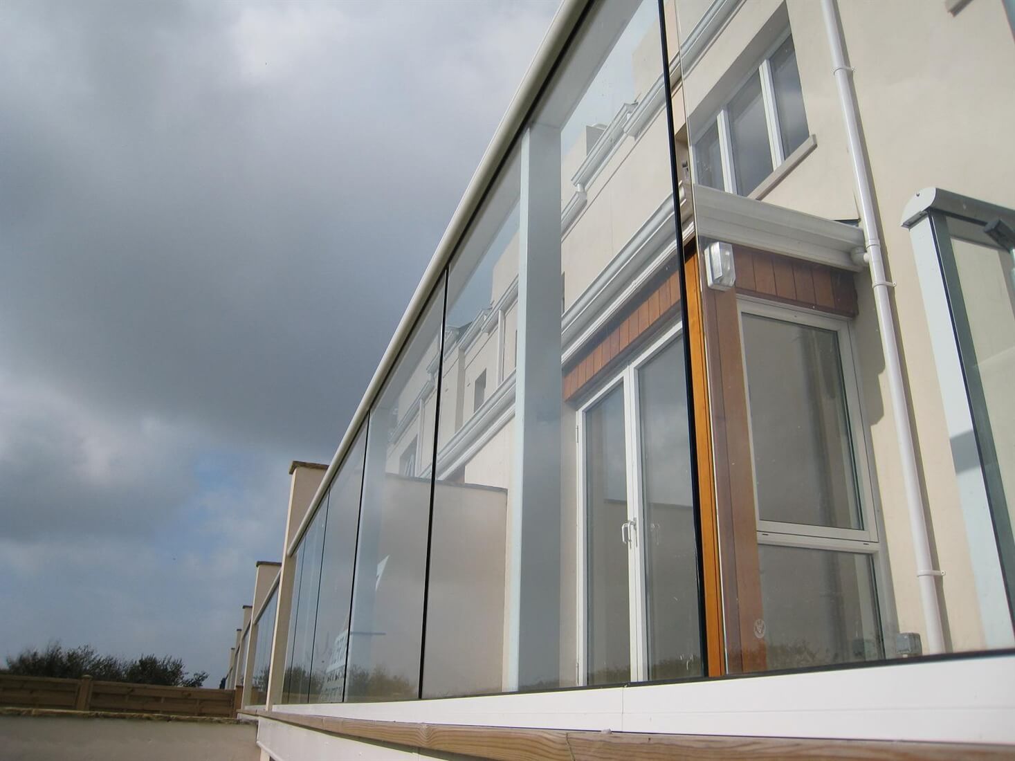 Looking side on at a clear glass balcony with white handrails
