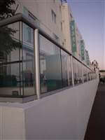 Side view of long restaurant balcony by the sea with silver handrails and posts