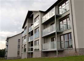 Looking side on at a large building on the riverside with Silver balustrades