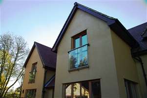 Silver Juliet balconies on a large house with blue skies