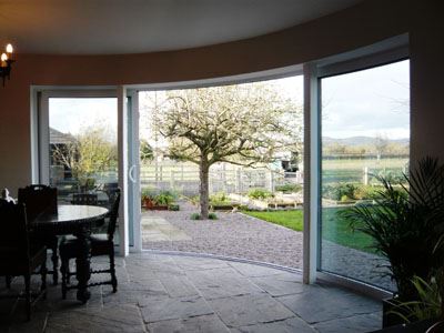 White Curved Doors opening onto a beautiful garden with a tree in the center.