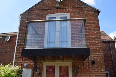 A below shot of a Hybrid balustrade system with a chrome aerofoil handrail