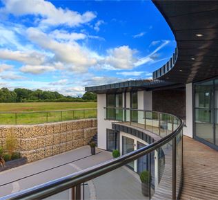 Curved Orbit Glass Balustrading overlooks the grounds at this striking two-storey property standing over eight acres on the site of a former piggery near the village of Slinfold