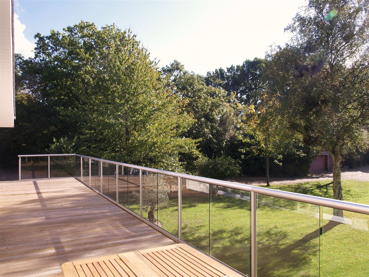 A Silver Orbit Glass Balustrade overlooking a beautiful tree filled garden