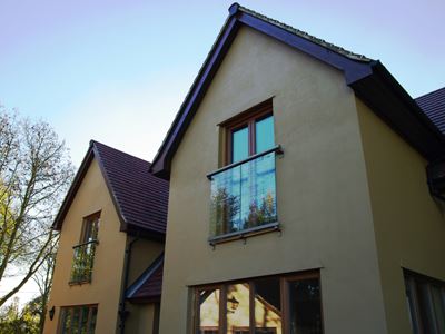 Silver Orbit Juliet Balcony installed on a large house surrounded by clear blue skies