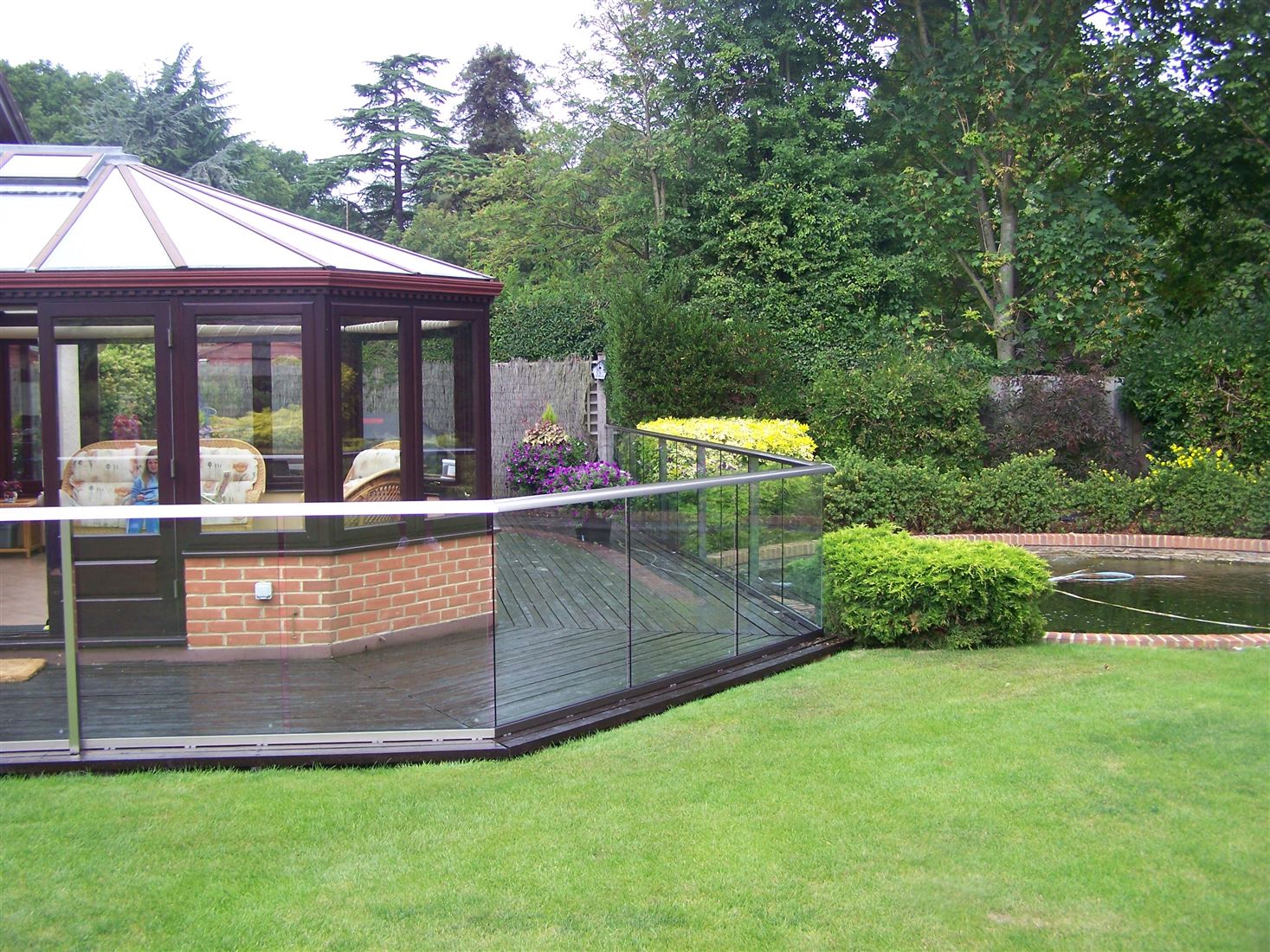 Aerofoil Glass Balustrade overlooking the well manicured garden with a pond