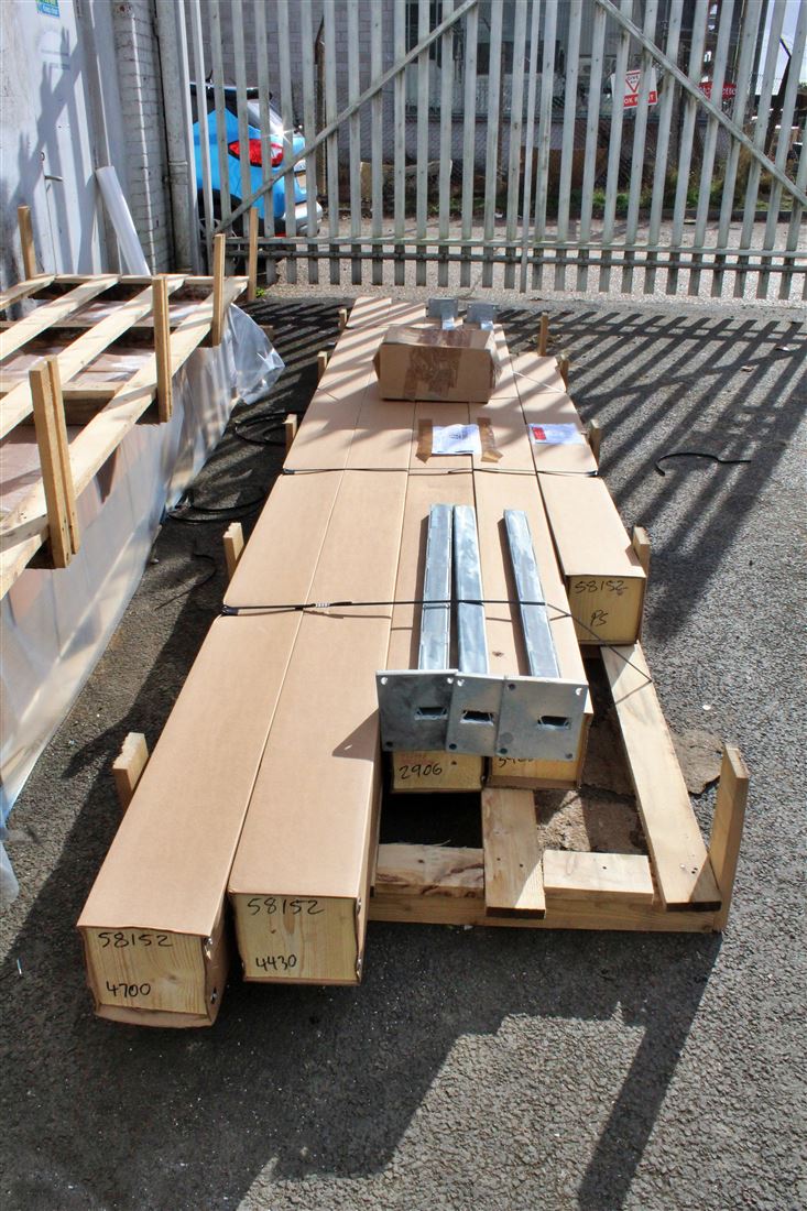 Packaged Balcony metalwork (profiles, bottom rail, post covers etc), galvanised steel posts and assembly accessory box strapped onto an oversized pallet