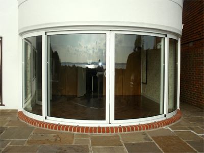 Simple looking Curved Glass Patio Door installed on a white house