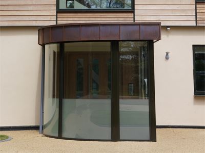 unique shape curved glass door on a wooden panelled building