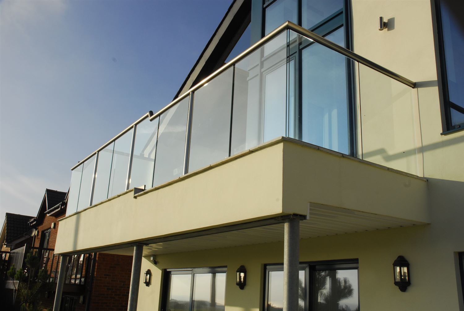 Royal Chrome Orbit Glass Balustrade installed on an intricately designed house 
