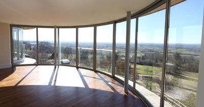 Curved Glass Sliding Doors looking out onto a countryside view. 