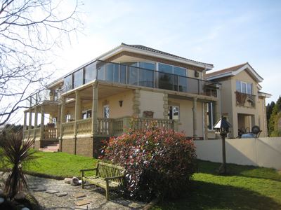 Large house with Bronze Aerofoil Glass Balustrade with grey tinted glass, surrounded by beautiful views