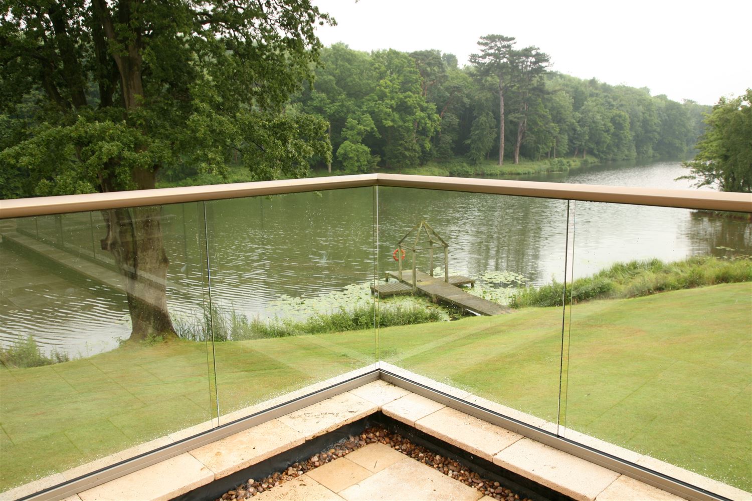 A Bronze Aerofoil Glass Balustrade overlooking a serene river view