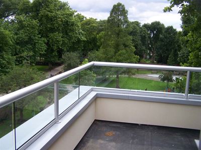 Corner countryside view through short clear glass balustrade with silver handrails and posts