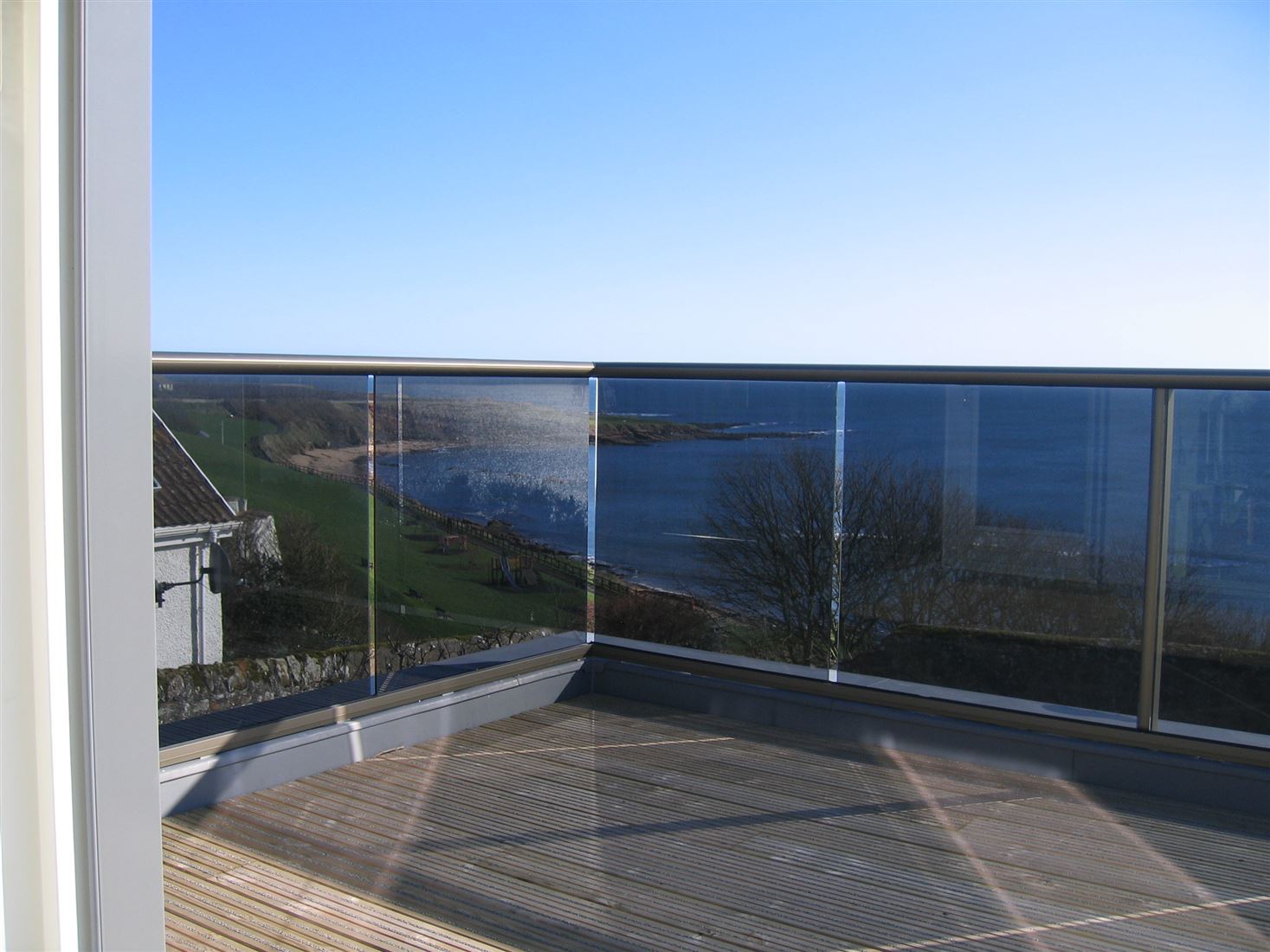 A glass balustrade with grey tinted 10mm toughened glass overlooking the sea