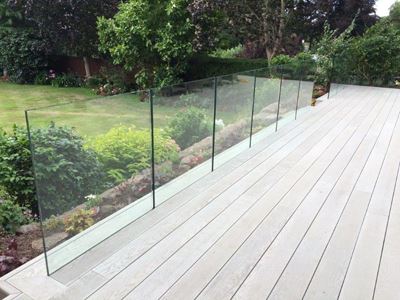Frameless Balustrade with the bottom rail below the wooden decking, looking over a large garden