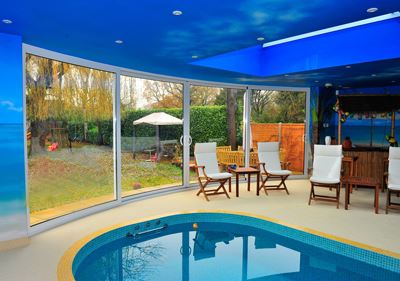 White Curved Glass Sliding Doors installed in a pool room