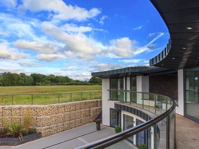 Curved Orbit Glass Balustrading overlooks the grounds at this striking two-storey property standing over eight acres on the site of a former piggery near the village of Slinfold
