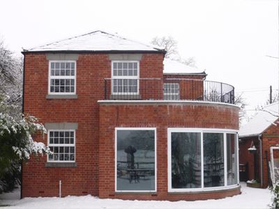 House with a curved glass door on the right side covered in snow